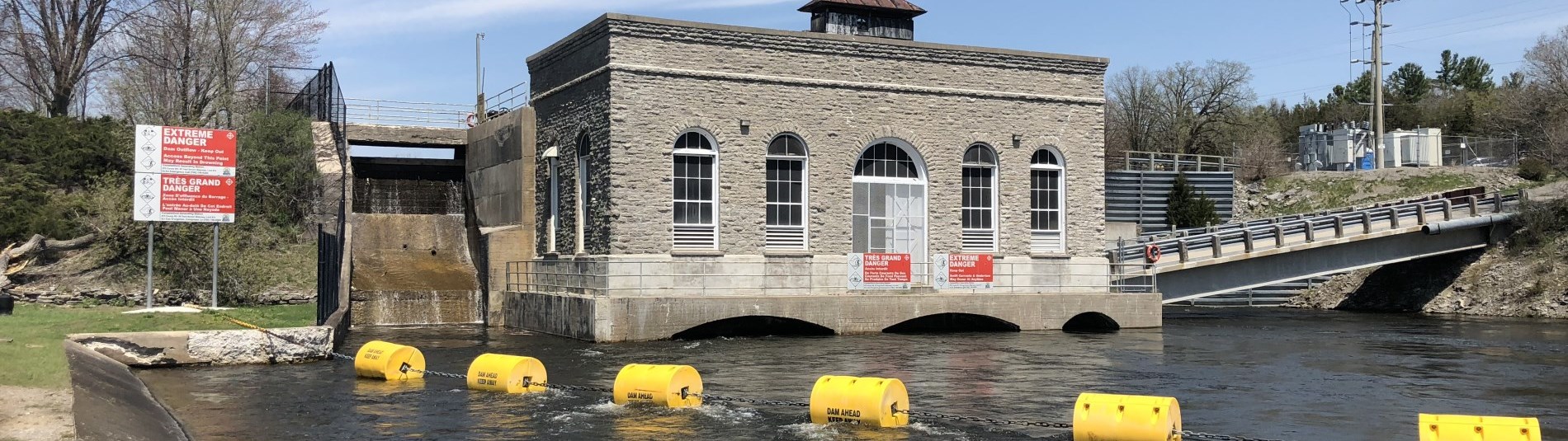 Public safety signs and in-water booms at a powerhouse