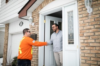 Peterborough Utilities employee shaking the hands of a man in the doorway of his home